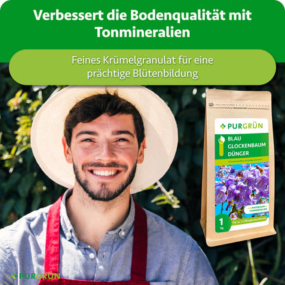 Ein lächelnder Mann mit Strohhut und roter Schürze steht im Freien neben einem 1-kg-Sack Purgrün Blauglockenbaum-Dünger mit blauen Blüten. Der Text oben wirbt für verbesserte Bodenqualität und besseres Pflanzenwachstum dank Tonmineralien.